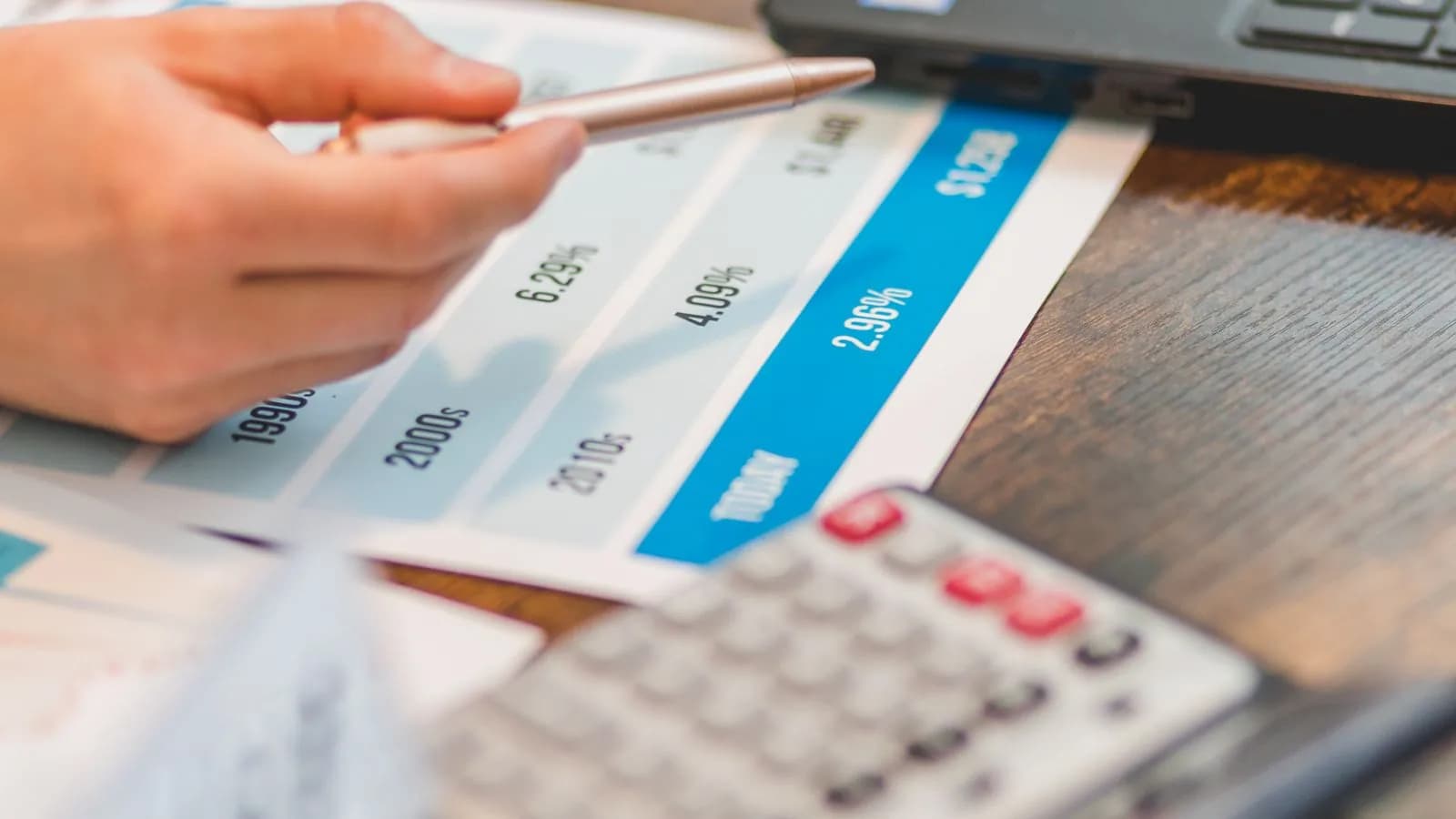Hand met pen vergelijkt rentetarieven naast een rekenmachine