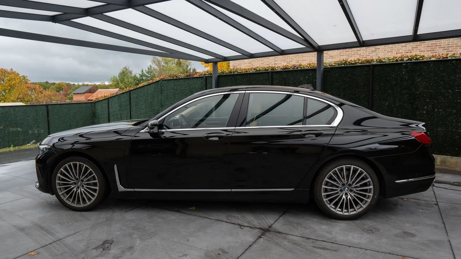 Zwarte sedan geparkeerd onder een glazen overkapping