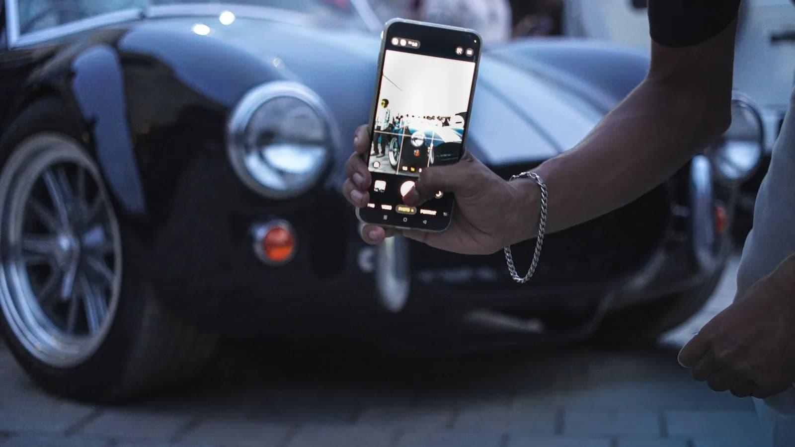 Iemand fotografeert een auto met een telefoon